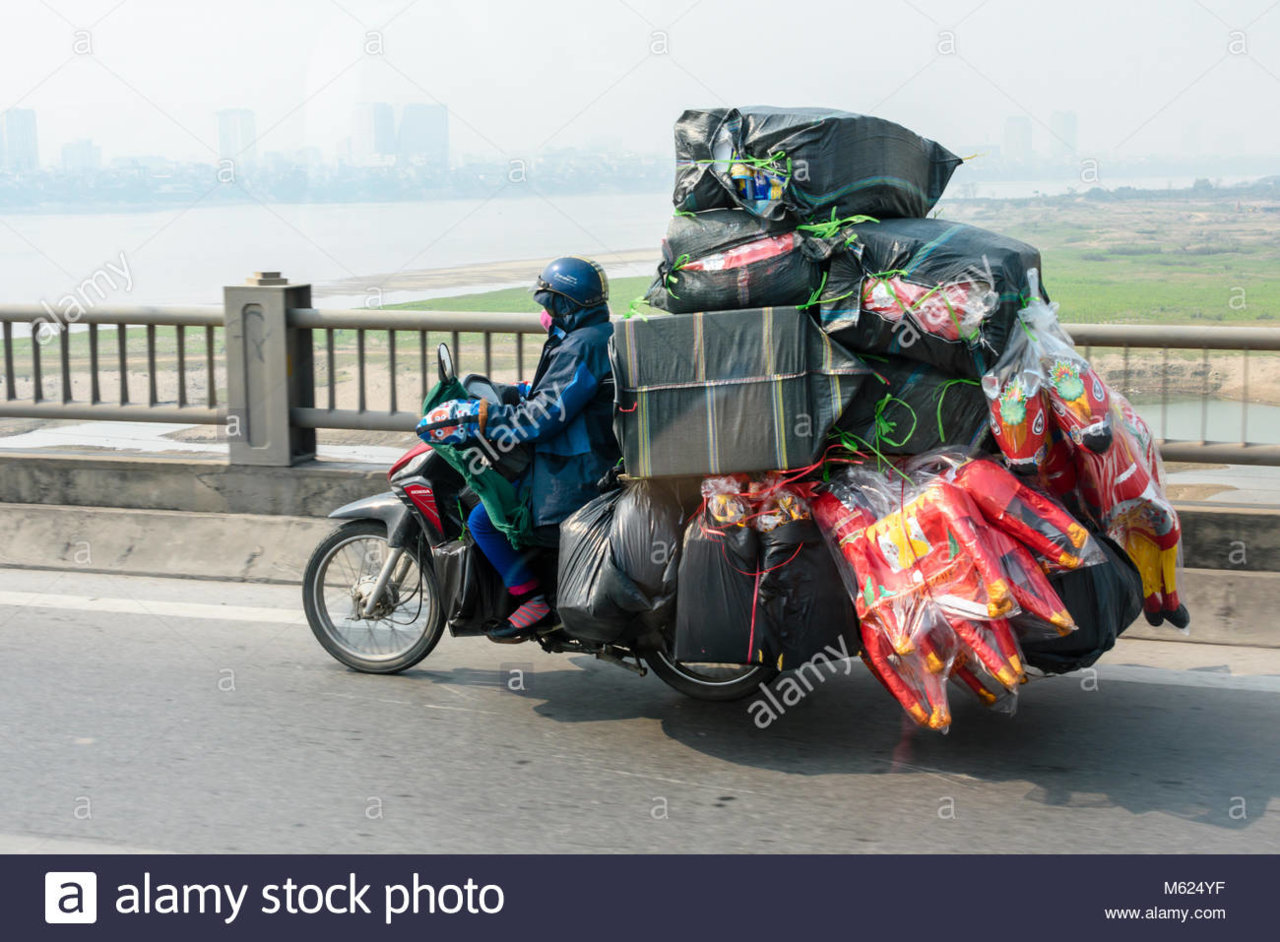 a-person-rides-a-scooter-with-a-very-heavy-load-of-goods-commonly-M624YF.jpg