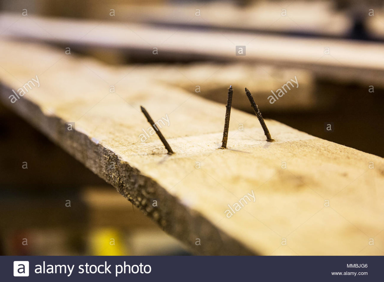 close-up-of-three-rusty-nails-sticking-out-of-a-wooden-plank-MMBJG6.jpg