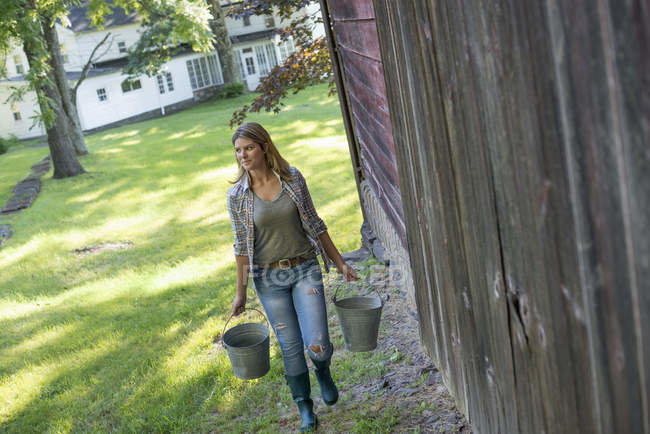 focused_193005520-stock-photo-woman-carrying-buckets-country-barn.jpg