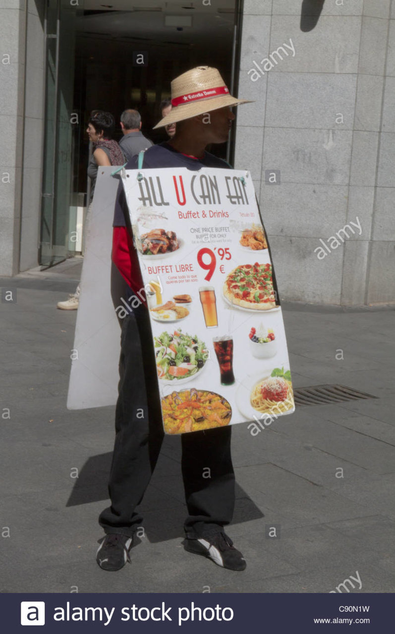man-carrying-advertising-sandwich-board-of-food-menu-sign-in-madrid-C90N1W.jpg