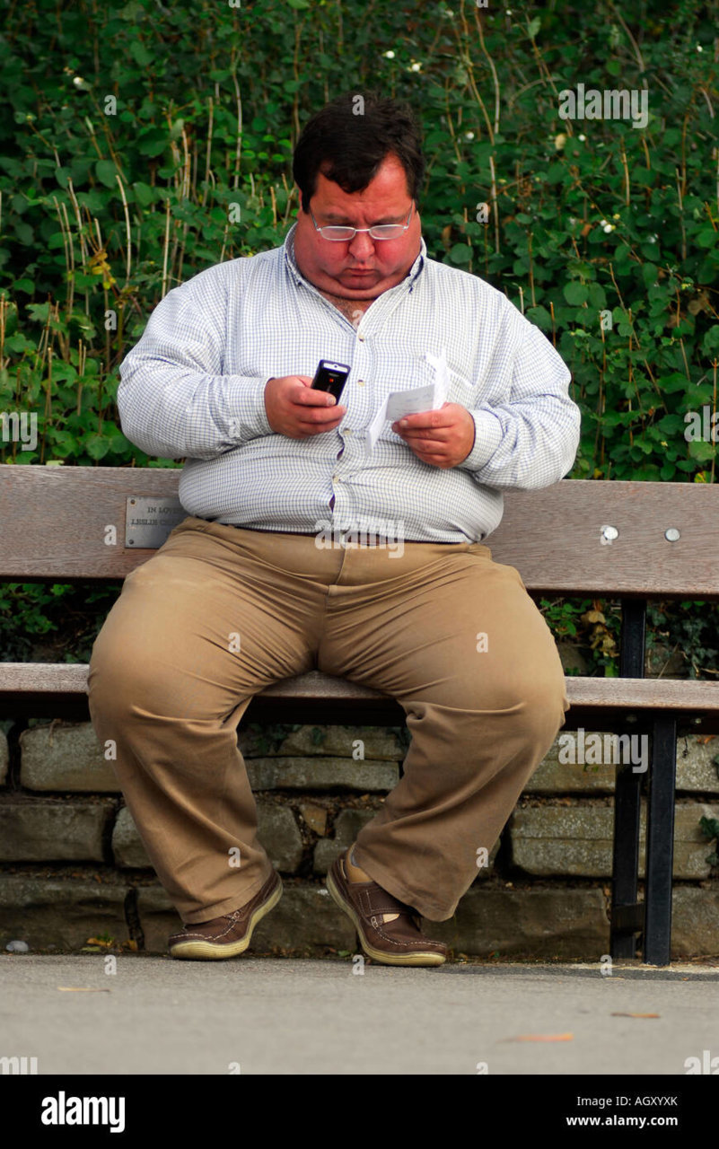 obese-man-sitting-on-a-park-bench-and-sending-a-text-message-from-AGXYXK.jpg