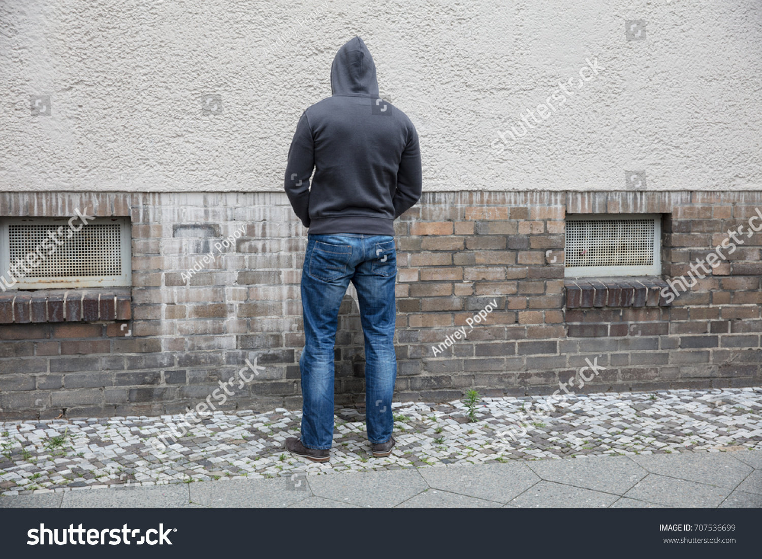 stock-photo-rear-view-of-a-man-in-hood-peeing-on-wall-in-street-707536699.jpg