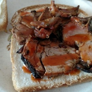 Bacon wrapped pork tenderloin sandwich with Texas Pete hot sauce sandwich