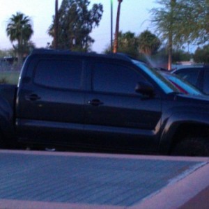 Black four door 4x4 wih black rims and cowboy stickers outside of roaring f