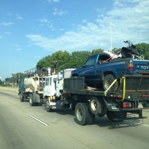 A truck towing a wheeler in a truck, loaded on a flatbed truck, on another 