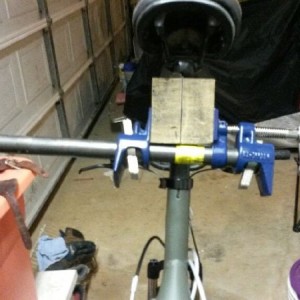 Bike rack using a pipe clamp and 4x4 post with hole drilled in it for seat 