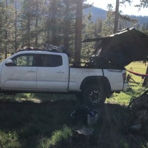 Tent set up on the back of truck so that the front panel is accessible.